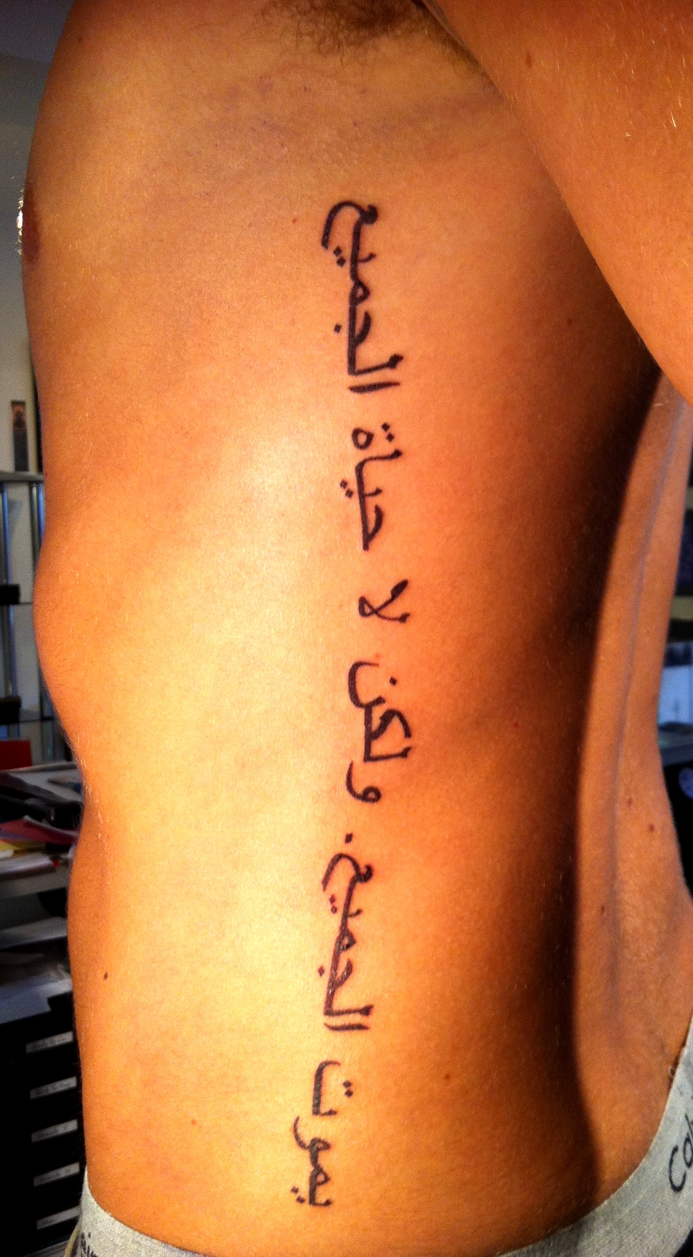 Arabic script tattoo idea on left ribs side for man