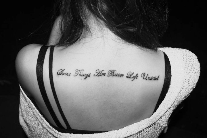 Script tattoo between shoulder blades