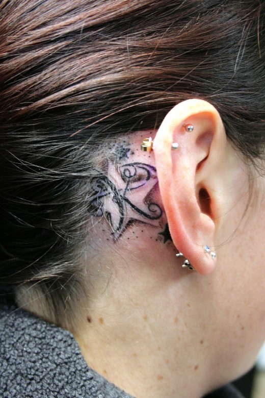 Letter-and-star back ear tattoo design for women
