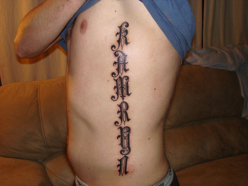 Fantasy font name tattoo on ribs for man