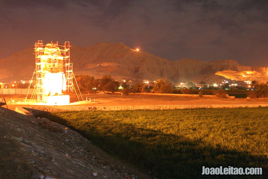 Um dos Colossos de Mêmnon e do Templo de Hatshepsut à noite