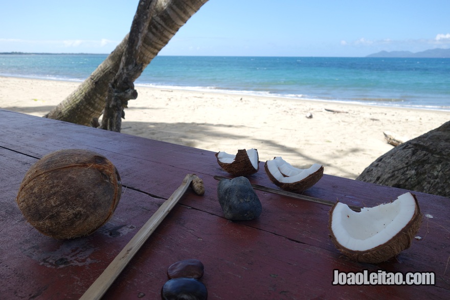 Arranjar ferramentas para abrir cocos na praia