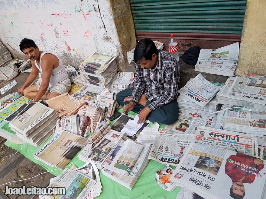 Homens a dobrar jornais na rua em Calcutá