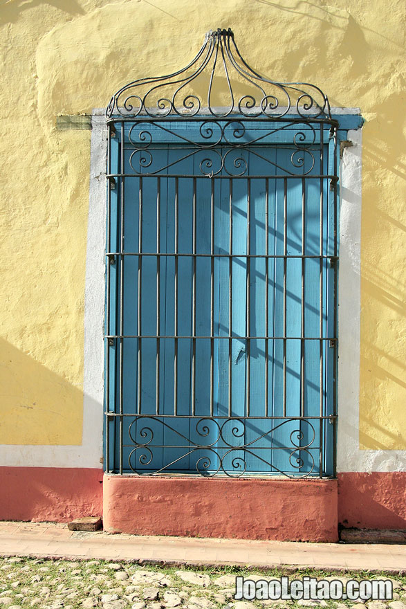 Janela azul em edifício amarelo em Trinidad