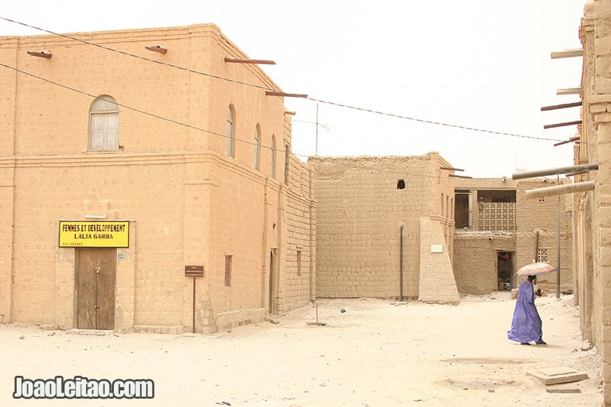 Man with umbrella going inside a mosque in Timbuktu