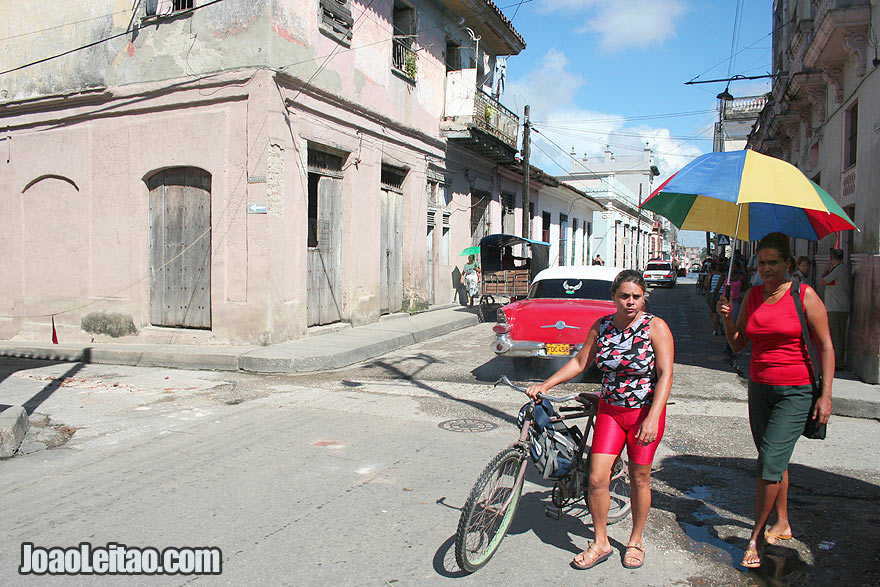 Remedios Street scene with red car and woman on a bicycle