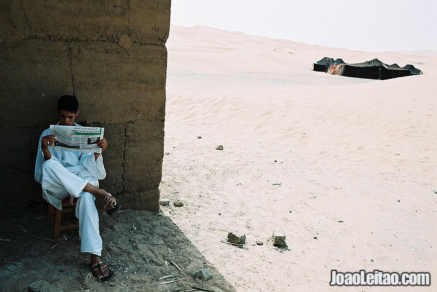 Photo of boy reading the newspaper in Sahara Desert, Morocco